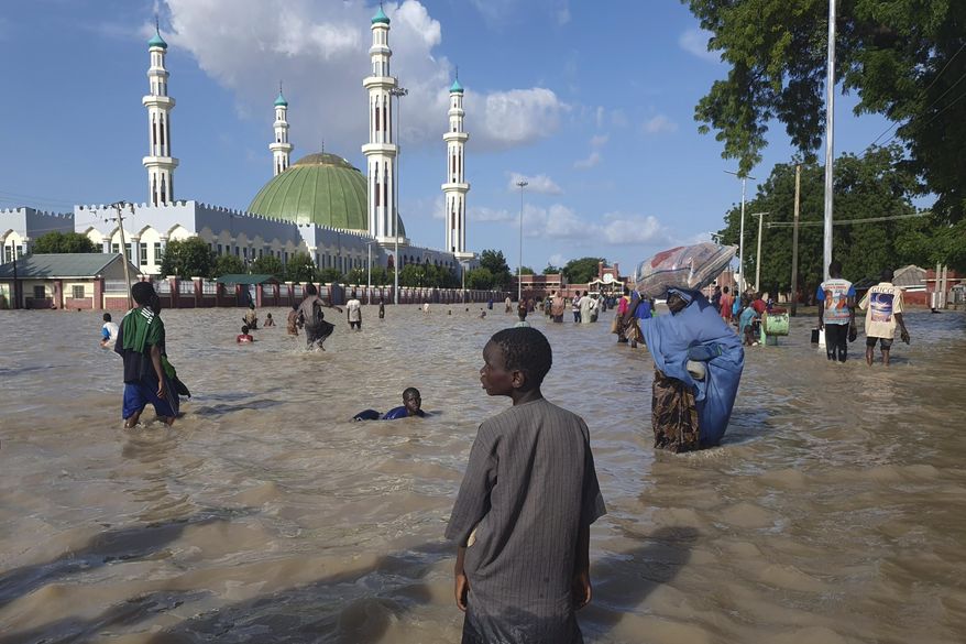 People walk through floodwaters following a dam collapse in Maiduguri, Nigeria, Tuesday, Sept 10, 2024. (AP Photos/ Joshua Olatunji, File)
