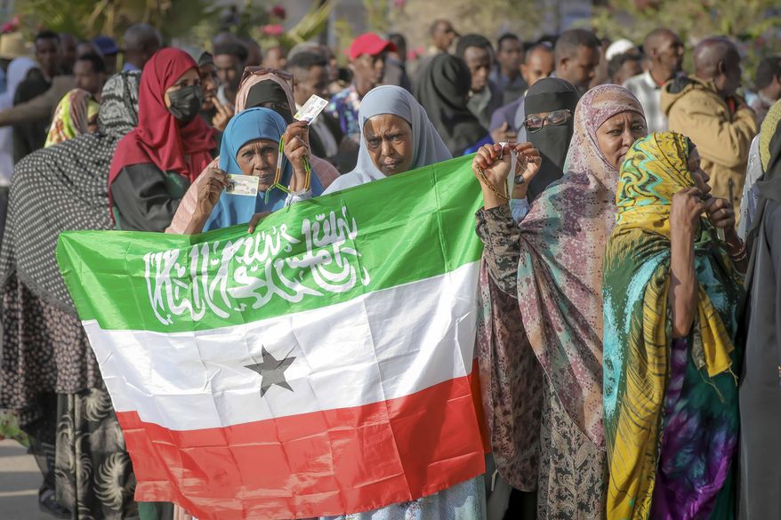 A woman displays the Somaliland flag as people queue to cast their votes during the 2024 Somaliland presidential election at a polling station in Hargeisa, Somaliland, Wednesday, Nov. 13, 2024. (AP Photo/Abdirahman Aleeli) ** FILE **
