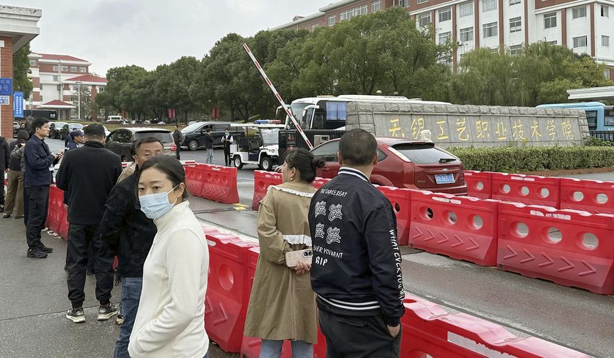 Guardians gather in front of the Wuxi Vocational Institute of Arts and Technology in Yixing, eastern Chinese city of Wuxi Sunday, Nov. 17, 2024, a day after a stabbing attack took place. (Kyodo News via AP)
