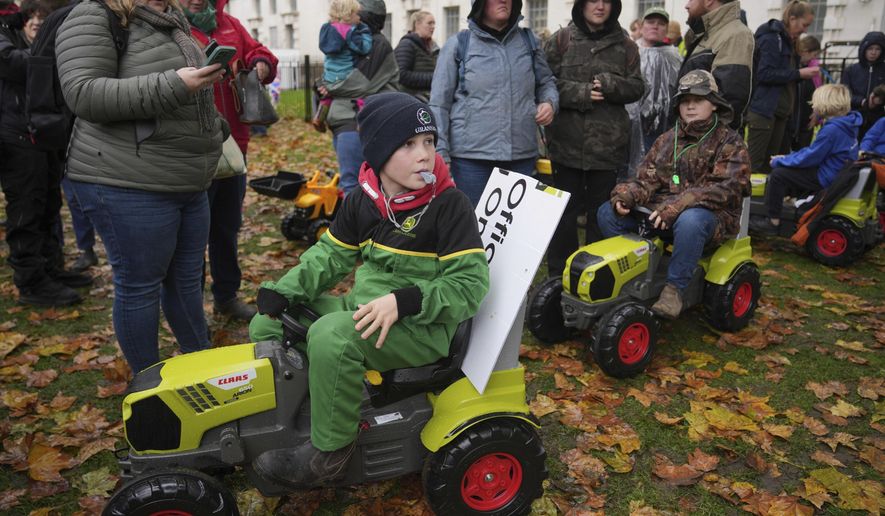 Seth James, left, and Eddie England, right, accompanied with their parents, attend a farmers protest to urge the government to change course over its inheritance tax plans, in London, Tuesday, Nov. 19, 2024. (AP Photo/Kin Cheung)