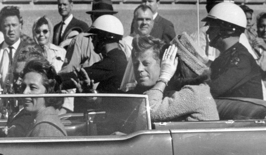 President John F. Kennedy waves from his car in a motorcade approximately one minute before he was shot, Nov. 22, 1963, in Dallas. (AP Photo/Jim Altgens, File)