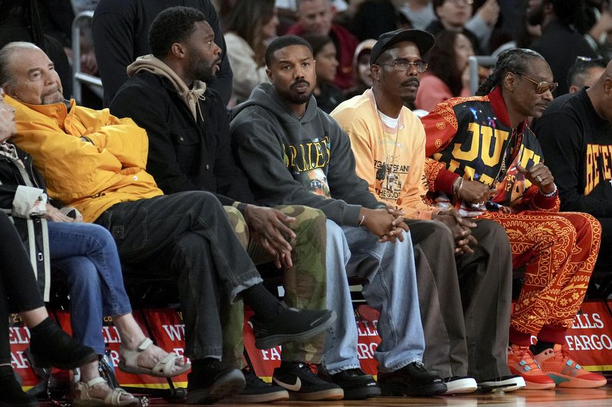 Actor Michael B. Jordan, center, sits on the sideline during the first half of an NCAA college basketball game between Southern California and Notre Dame Saturday, Nov. 23, 2024 in Los Angeles. (AP Photo/Eric Thayer)