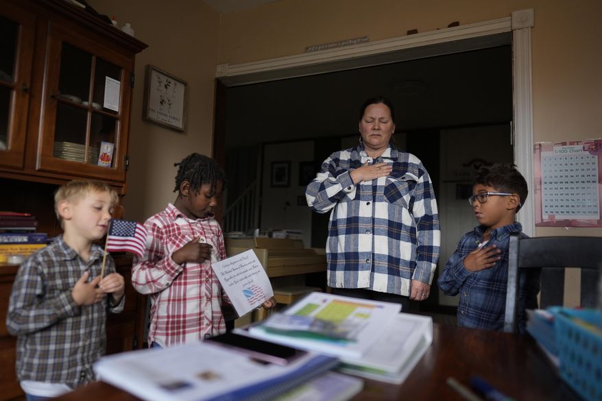 With hands over their hearts, Erin Young and her three adopted children from left, Isaac, 5, Gianna, 7, and Lucas, 8, say the Pledge of Allegiance as they begin their homeschooling lessons, Tuesday, Nov. 12, 2024, in Sunbury, Ohio. (AP Photo/Carolyn Kaster)