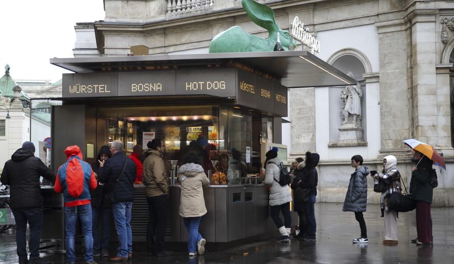 Customers line up at a traditional sausage stand (Wuerstelstand), which are named as intangible cultural heritage by the Austrian UNESCO Commission, in Vienna, Austria, Thursday, Nov. 28, 2024. (AP Photo/Heinz-Peter Bader)