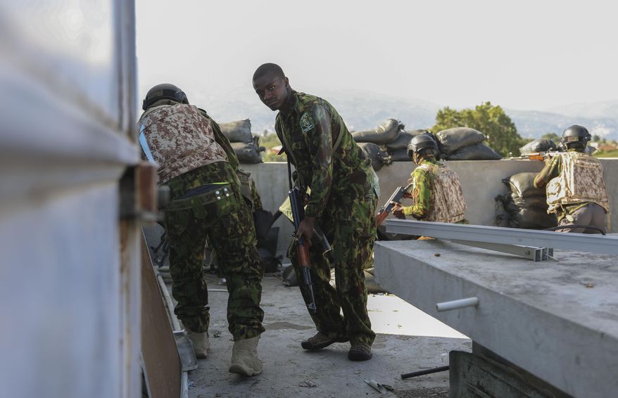 Kenyan police officers, part of a UN-backed multinational force, take cover from an exchange of gunfire between gangs and police at a Kenyan police base in the Delmas neighborhood of Port-au-Prince, Haiti, Thursday, Dec. 5, 2024. (AP Photo/Odelyn Joseph)