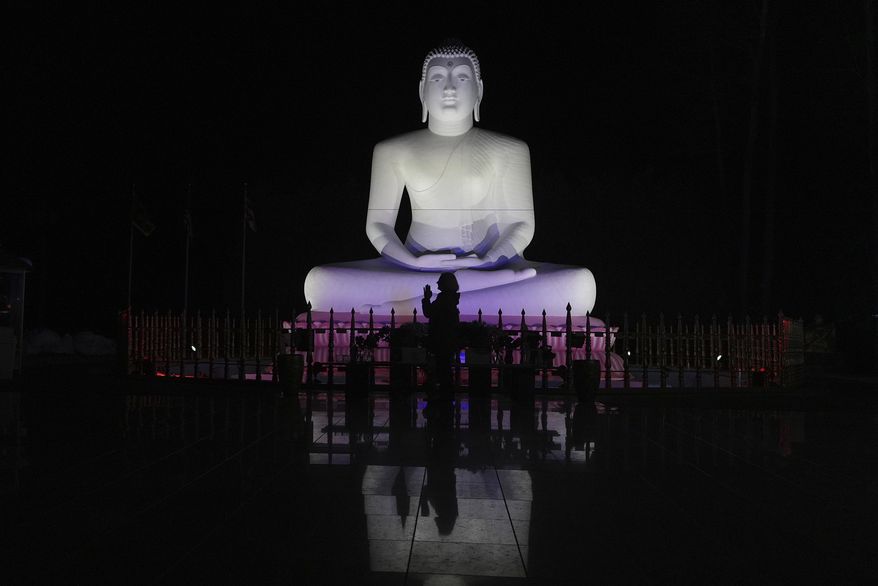 Carol Kruhen lifts up her pressed palms next to a statue of the Buddha after meditating at the New Jersey Buddhist Vihara and Meditation Center in Franklin Township, N.J. on Sunday Nov. 30, 2024. (AP photo/Luis Andres Henao)