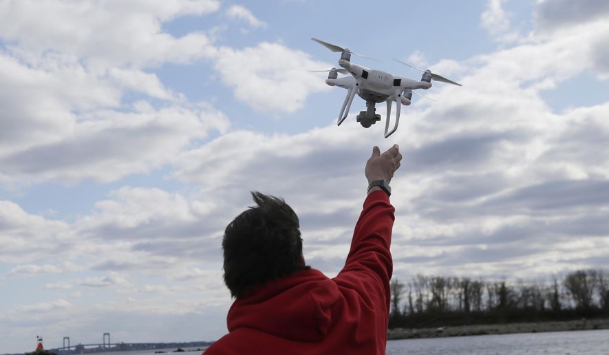 FILE - In this April 29, 2018, file photo, a drone operator helps to retrieve a drone after photographing over Hart Island in New York. (AP Photo/Seth Wenig, File)