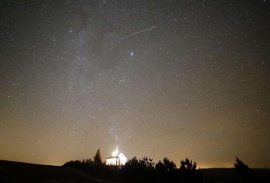 FILE - A meteor streaks across the sky during the annual Geminids meteor shower over an Orthodox church on the local cemetery near the village of Zagorie, Belarus, late, Dec. 13, 2017. (AP Photo/Sergei Grits, File) **FILE**