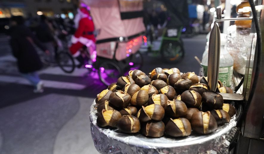 Chestnuts are displayed at a food vendor as a person dressed as Santa Claus offers rides, Thursday, Dec. 12, 2024, in New York. (AP Photo/Alyssa Goodman)