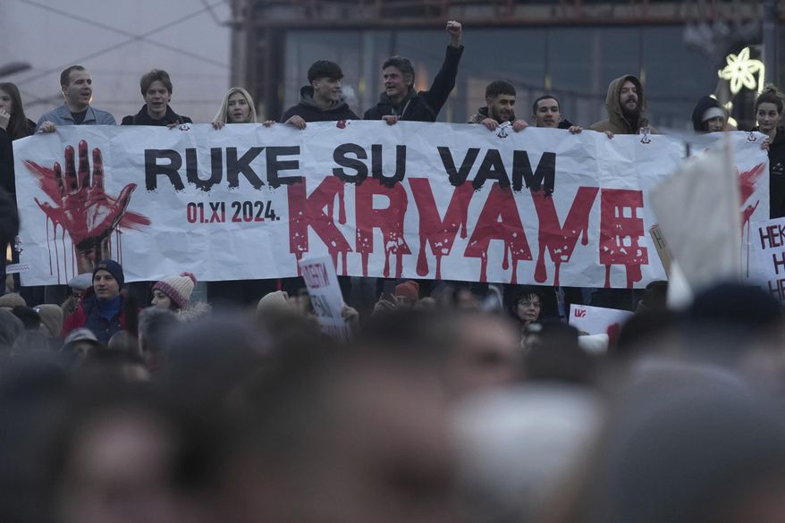 People hold a banner that reads "You have blood on your hands" during a protest against the Serbian authorities in Belgrade, Serbia, Sunday, Dec. 22, 2024. (AP Photo/Darko Vojinovic)