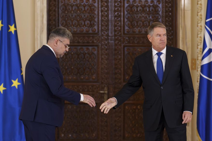 Romanian President Klaus Iohannis, right, walks after shaking hands with Prime Minister designate Marcel Ciolacu, left, after nominating him to form the new government in Bucharest, Romania, Monday, Dec. 23, 2024. (AP Photo/Vadim Ghirda)