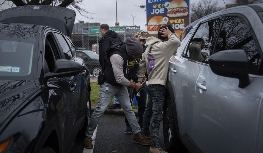 A deportation officer with Enforcement and Removal Operations in U.S. Immigration and Customs Enforcement's New York City field office changes the handcuffs of Wilmer Patricio Medina-Medina from back to front after arresting him during an early morning operation, Tuesday, Dec. 17, 2024, in the Bronx borough of New York. (AP Photo/Julia Demaree Nikhinson)