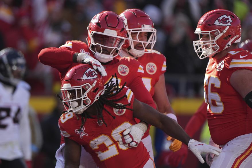 Kansas City Chiefs running back Kareem Hunt, front, is congratulated by teammates after scoring during the first half of an NFL football game against the Houston Texans Saturday, Dec. 21, 2024, in Kansas City, Mo. (AP Photo/Charlie Riedel)