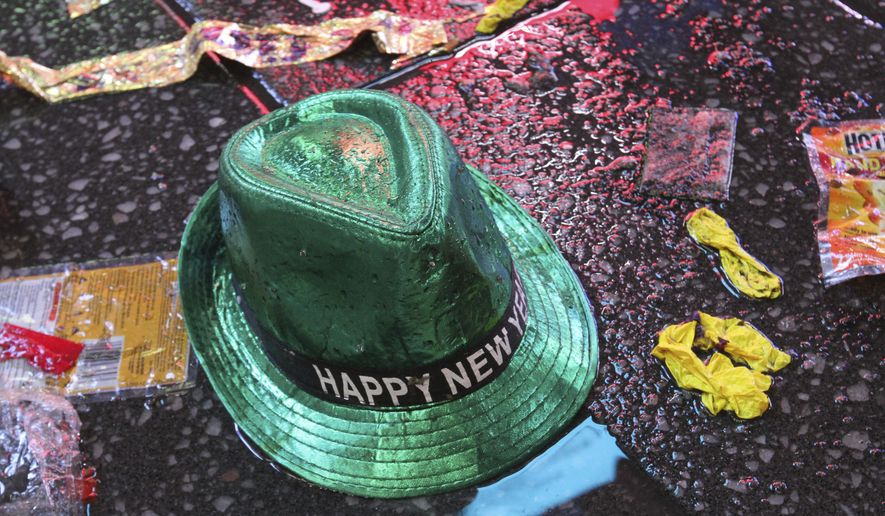 FILE - In this Jan. 1, 2019, file photo a "Happy New Year" hat lies on the wet ground along with other items following the celebration in New York's Times Square. (AP Photo/Tina Fineberg, File)