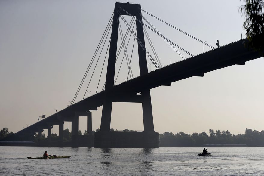 FILE - Two people canoe under the Hale Boggs Memorial Bridge in the Mississippi River in Luling, La., July 25, 2014. (AP Photo/Gerald Herbert, File)