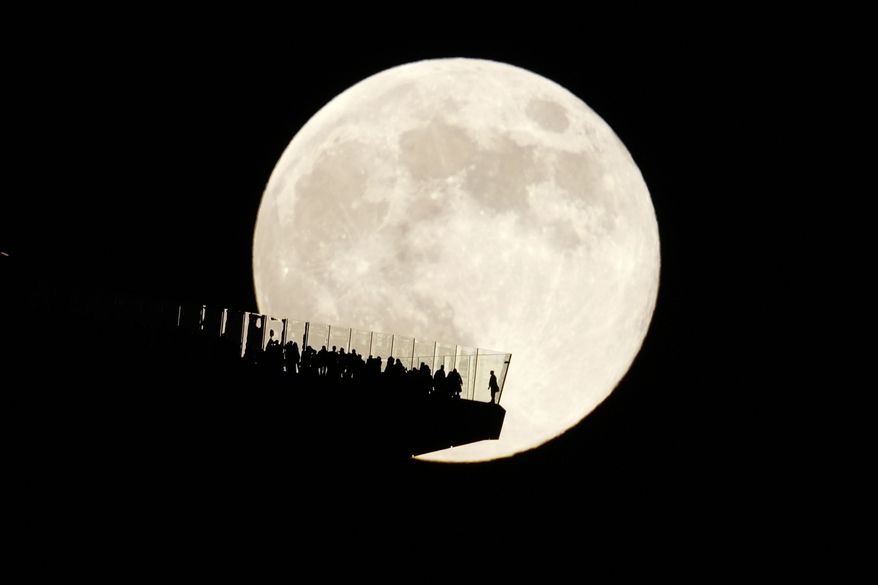 FILE - A supermoon rises behind an observation deck in New York City as seen from Hoboken, N.J., Friday, Nov. 15, 2024. (AP Photo/Seth Wenig, File)