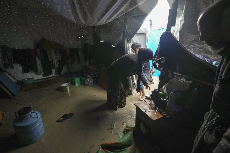 Manal Lubbad, a 49-year-old mother of eight and a displaced woman from Gaza City, tries to clean her flooded tent after heavy overnight rainfall at the refugee tent camp for displaced Palestinians in Deir al-Balah, central Gaza Strip, Tuesday, Dec. 31, 2024. (AP Photo/Abdel Kareem Hana)