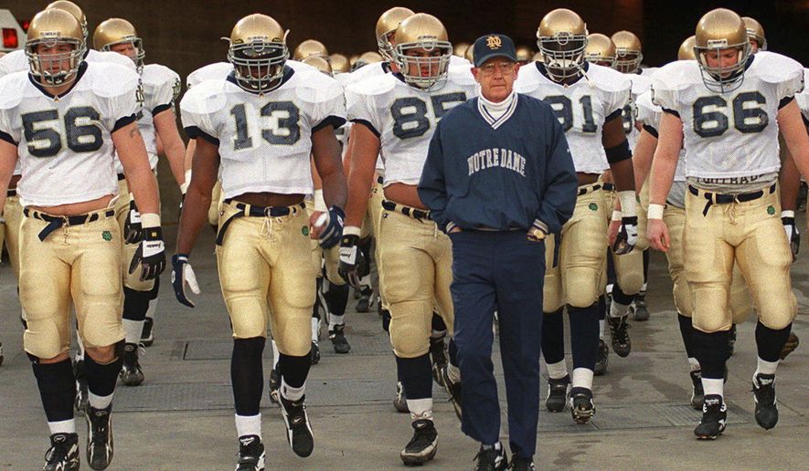 Notre Dame's head coach Lou Holtz and the Fighting Irish walk onto the field of the Los Angeles Coliseum to warm up for an NCAA college football game against Southern California Saturday, Nov. 30, 1996 in Los Angeles. (AP Photo/Kevork Djansezian, File)