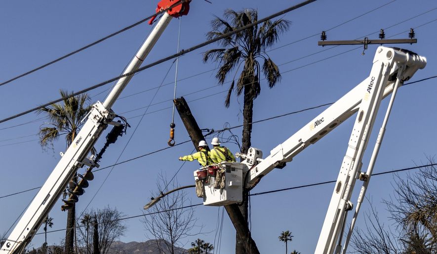 Workers with Southern California Edison remove a utility pole damaged by the Eaton Fire in Altadena, Calif., Sunday, Jan. 12, 2025. (Stephen Lam/San Francisco Chronicle via AP)