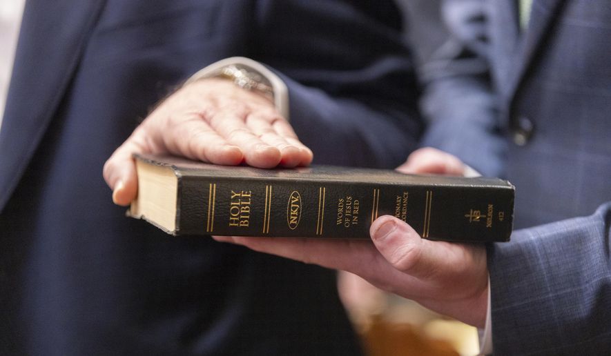 A legislator puts their hand on a Bible during a swearing-in ceremony on the first day of the legislative session at the Capitol in Atlanta, Monday, Jan. 13, 2025. (Arvin Temkar/Atlanta Journal-Constitution via AP) ** FILE **