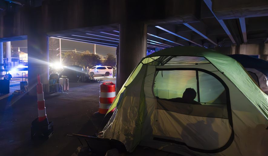 Homeless people wake up in the early morning as Louisiana State Troopers pull up underneath the Pontchartrain Expressway in downtown New Orleans on Wednesday, Jan. 15, 2025. (Chris Granger/The Times-Picayune/The New Orleans Advocate via AP) **FILE**
