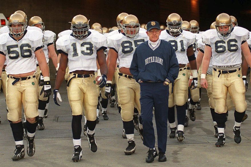 FILE - Notre Dame's head coach Lou Holtz and the Fighting Irish walk onto the field of the Los Angeles Coliseum to warm up for an NCAA college football game against Southern California Saturday, Nov. 30, 1996 in Los Angeles. (AP Photo/Kevork Djansezian, File)
