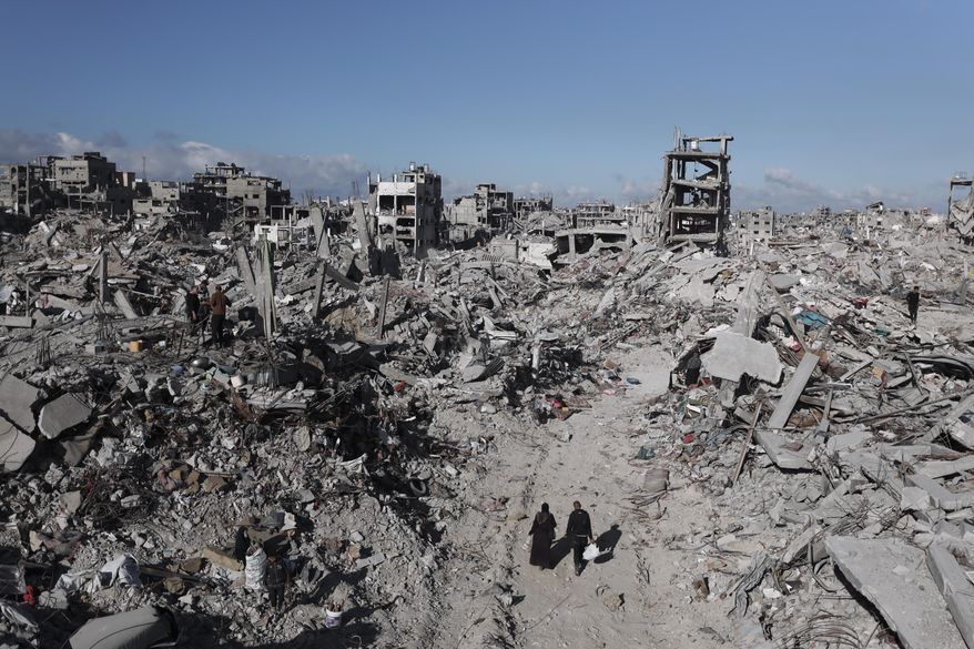 Palestinians walk through the destruction caused by the Israeli air and ground offensive in Jabaliya, a day after the ceasefire deal between Israel and Hamas came into effect, Monday, Jan. 20, 2025. (AP Photo/Abed Hajjar)