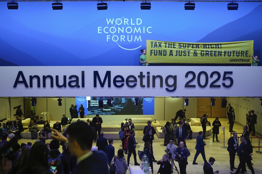 Greenpeace activists show a poster during a protest at the Annual Meeting of World Economic Forum in Davos, Switzerland, Tuesday, Jan. 21, 2025. (AP Photo/Markus Schreiber)
