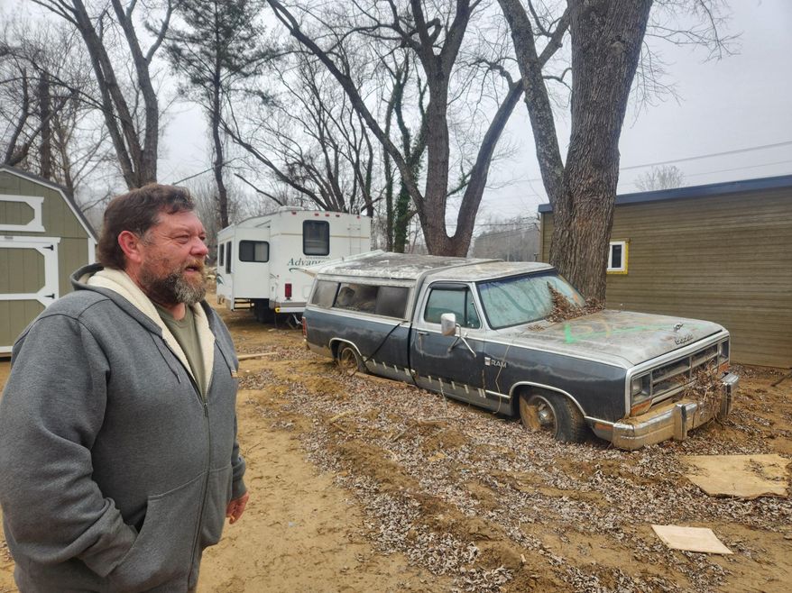 Danny Bailey stands in front of the donated camper he lives in — and the flooded truck he was planning to sell before the flood. "Now I'm just waiting around on my nephew to come and take it for parts," he said. "No good for nothing else." Photo credit: Emma Ayers / The Washington Times