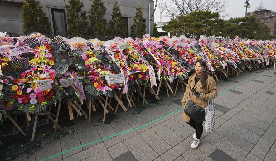 A pedestrian passes by the wreaths sent by supporters of impeached South Korean President Yoon Suk Yeol outside of the Constitutional Court in Seoul, South Korea, Jan. 14, 2025. (AP Photo/Lee Jin-man, File)