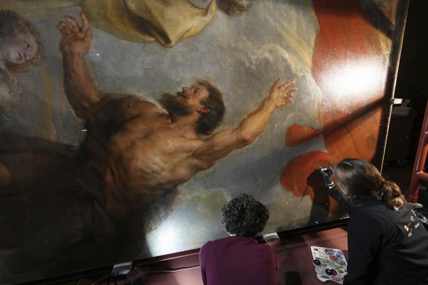 Art conservators Jill Keppens, left, and Kayla Metelenis, right, work on sections of the Enthroned Madonna Adored by Saints, painted by Flemish artist Peter Paul Rubens, at the Royal Museum of Fine Arts in Antwerp, Belgium, Tuesday, Jan. 28, 2025. (AP Photo/Virginia Mayo)