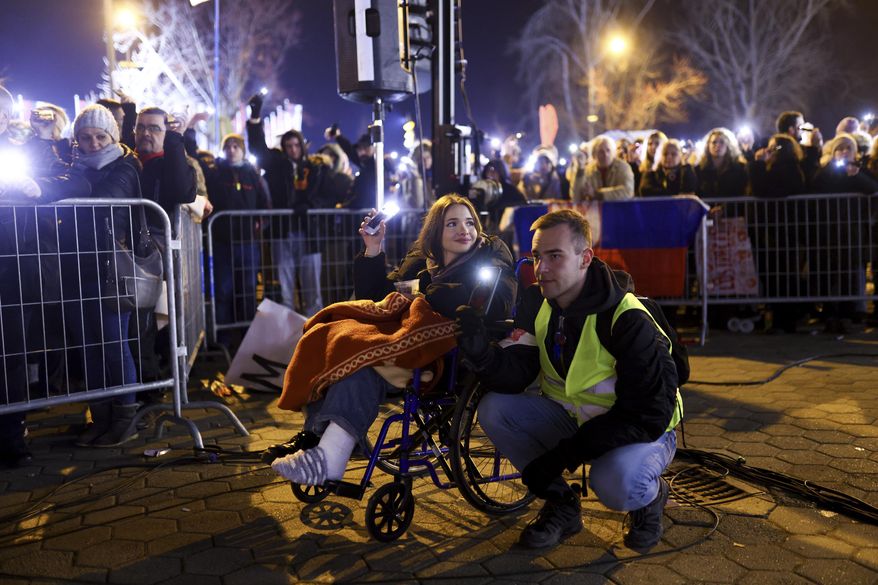 People hold up their mobile phone lights during a minute of silence ceremony as they block the bridge during a protest over the collapse of a concrete canopy that killed multiple people more than two months ago, in Novi Sad, Serbia, Sunday, Feb. 2, 2025. (AP Photo/Armin Durgut)