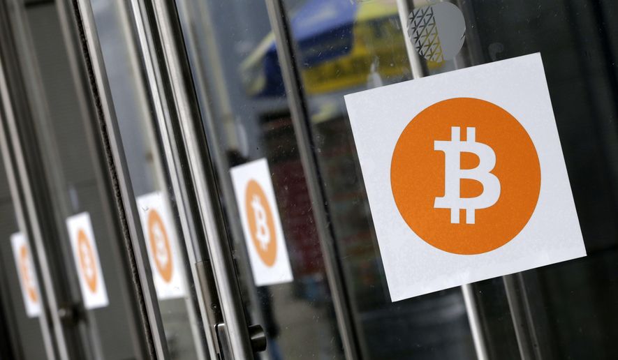 Bitcoin logos are displayed at the Inside Bitcoins conference and trade show in New York on April 7, 2014. (AP Photo/Mark Lennihan) **FILE**