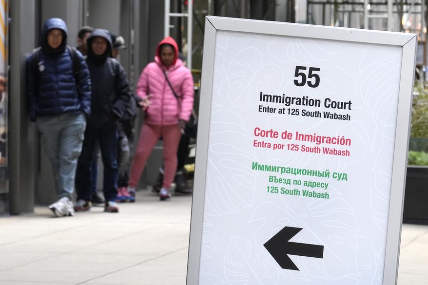 People wait in a queue before being led into a downtown Chicago building where an immigration court presides in Chicago on Tuesday, Nov. 12, 2024. (AP Photo/Charles Rex Arbogast) ** FILE **