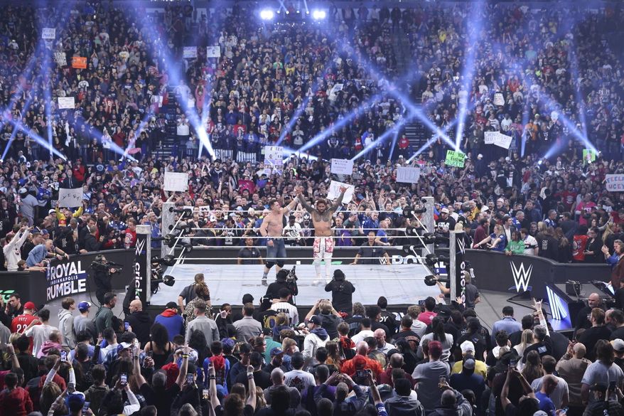 This image provided by the WWE shows John Cena holding up the arm of Jey Uso during a Royal Rumble event in Indianapolis. (WWE via AP)
