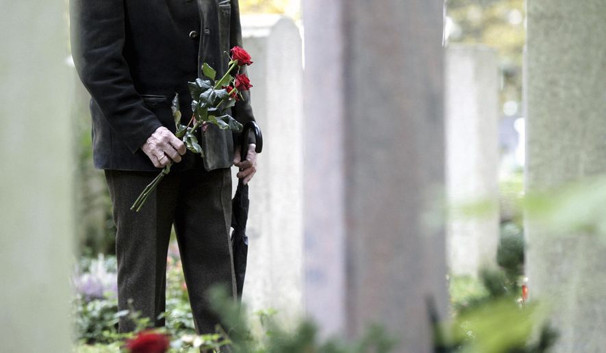 A man stands in front of gravestones at the Waldfriedhof cemetery in Munich, Germany, Wednesday, Nov. 1, 2006. (AP Photo/Christof Stache, File)