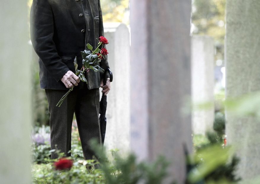 A man stands in front of gravestones at the Waldfriedhof cemetery in Munich, Germany, Wednesday, Nov. 1, 2006. (AP Photo/Christof Stache, File)