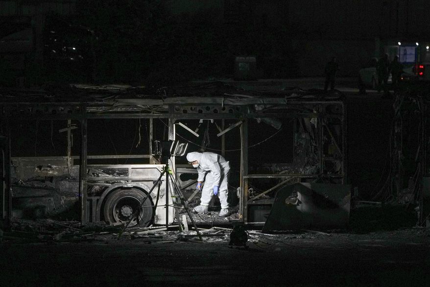 An Israeli police officer inspects the scene of one of a series of bus explosions in what authorities said appeared to be a militant attack in Bat Yam, central Israel, Thursday, Feb. 20, 2025. (AP Photo/Ohad Zwigenberg)