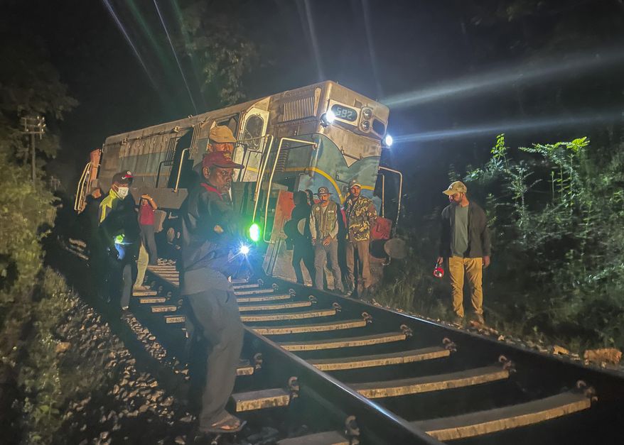 Wildlife and police officers stand next to a derailed train engine after it collided with a herd of wild elephants in Minneriya, Sri Lanka, Thursday, Feb. 20, 2025. (AP Photo/Priyan Malinda)