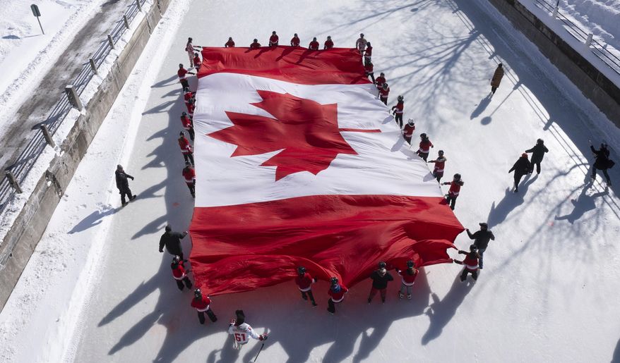 Local youth skate with a large Canadian flag on the Rideau Canal to launch celebrations for the 60th Anniversary of the National Flag of Canada Day, Friday, Feb. 14, 2025 in Ottawa. (Adrian Wyld/The Canadian Press via AP)