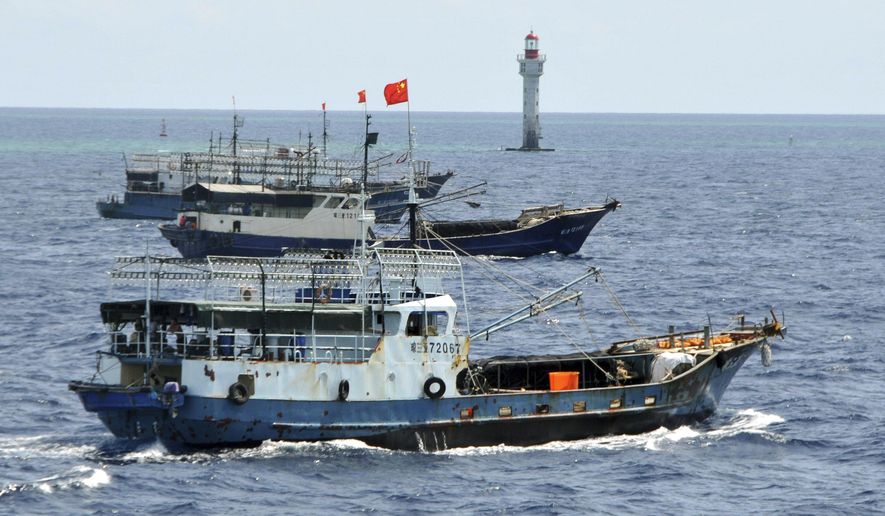 FILE - Chinese fishing vessels navigate past a beacon in the Zhubi Reef off Spratly Islands in South China Sea, July 18, 2012. (AP Photo/Xinhua, Wang Cunfu, File)