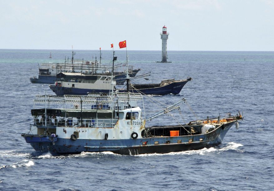 FILE - Chinese fishing vessels navigate past a beacon in the Zhubi Reef off Spratly Islands in South China Sea, July 18, 2012. (AP Photo/Xinhua, Wang Cunfu, File)