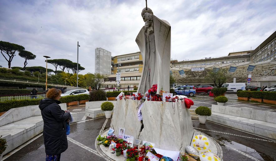 A woman prays for Pope Francis in front of the Agostino Gemelli Polyclinic, in Rome, where the Pontiff has been hospitalized since Feb. 14, Wednesday, Feb. 26, 2025. (AP Photo/Andrew Medichini)