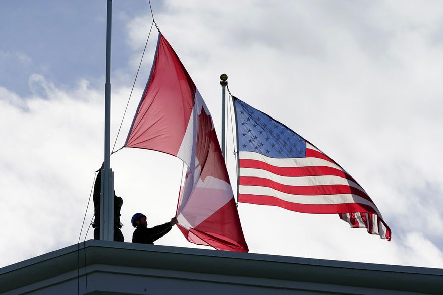 Washington State Park workers put up a new Canadian flag in front of an American flag about to be replaced during scheduled maintenance atop the Peace Arch in Peace Arch Historical State Park Monday, Nov. 8, 2021, in Blaine, Wash. (AP Photo/Elaine Thompson) **FILE**