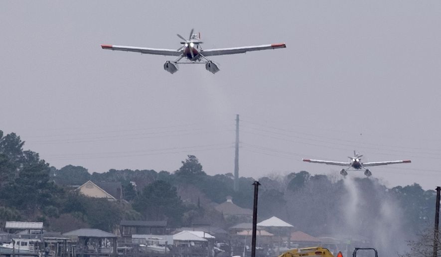 Planes fill bladders with water from the Intracoastal Waterway and empty the water on hot spots in the Carolina Forest wildfire Sunday, March 2, 2025, in Myrtle Beach, S.C. (Janet Morgan/The Post And Courier via AP)