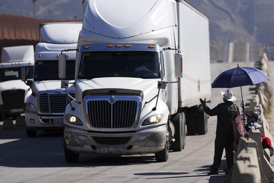Susano Cordoba, right, gestures towards trucks lining up to cross the border into the United States as tariffs against Mexico go into effect, Tuesday, March 4, 2025, in Tijuana, Mexico. (AP Photo/Gregory Bull)