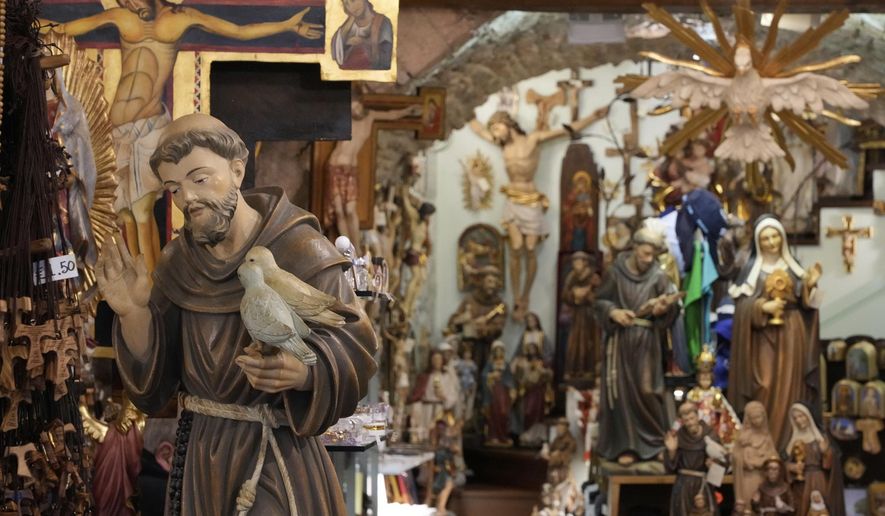 A votive statue of Italy's patron saint, St. Francis of Assisi, left, is on display among other religious items at a shop in Assisi, Italy, Saturday, March 1, 2025. (AP Photo/Gregorio Borgia)