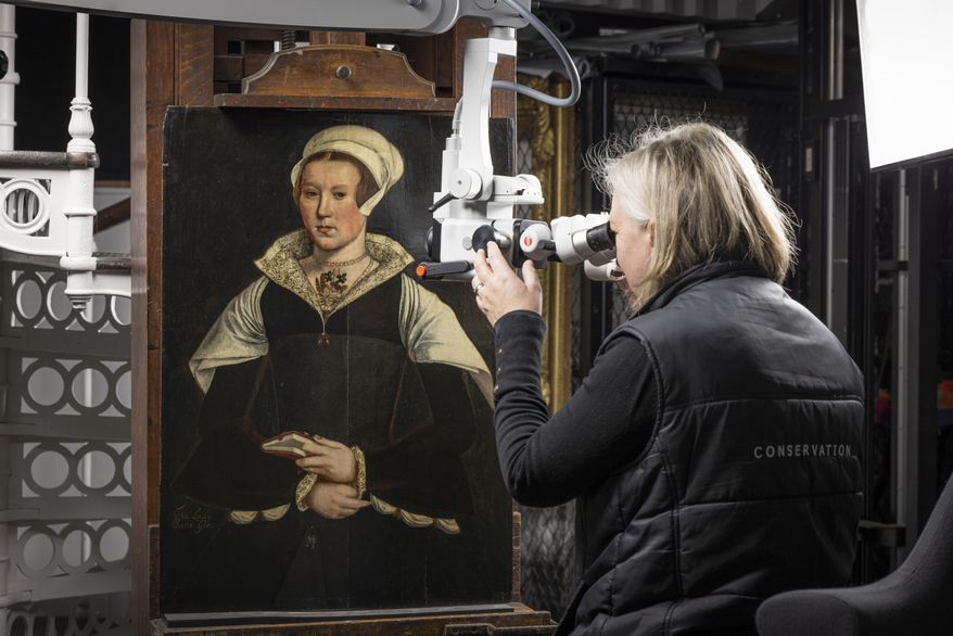 In this photo provided by English Heritage, English Heritage Conservator Rachel Turnbull gives a portrait believed to be of Lady Jane Grey a final examination before it goes on display at Wrest Park in Bedfordshire, England, Feb. 27, 2025. (Christopher Ison, English Heritage via AP)