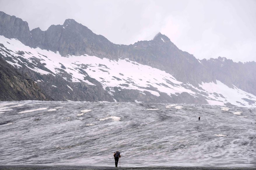 FILE - A cameraman walks up to the Rhone Glacier near Goms, Switzerland, Friday, June 16, 2023. (AP Photo/Matthias Schrader, File)