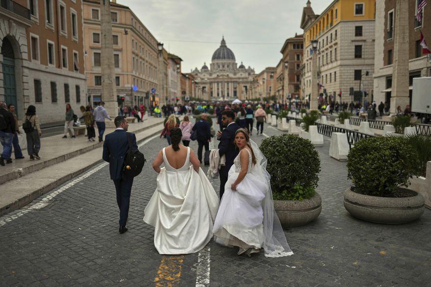 Locals and tourists walk along a main street near St. Peter's Basilica, background, in Rome, Saturday, March 8, 2025. (AP Photo/Francisco Seco)